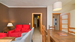 A living room with a red sofa, a grey sofa, a wooden dining table, and a lamp. - Rural house Montseny, Cal Metge (GUALBA)