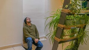 A person sitting against a wall in a room with a plant shelf and a tiled floor. - Rural house Montseny, Cal Metge (GUALBA)