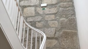 Una escalera con un muro de piedra, una barandilla blanca y una pequeña señal con una flecha.