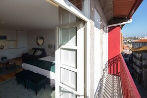 Un dormitorio con cama, escritorio y ventana con vista a un paisaje urbano.
