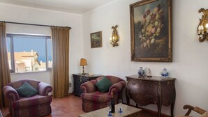 A living room with two armchairs, a sofa, a coffee table, and a painting on the wall.