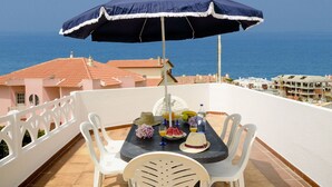 A terrace with a table set for two, overlooking the sea.