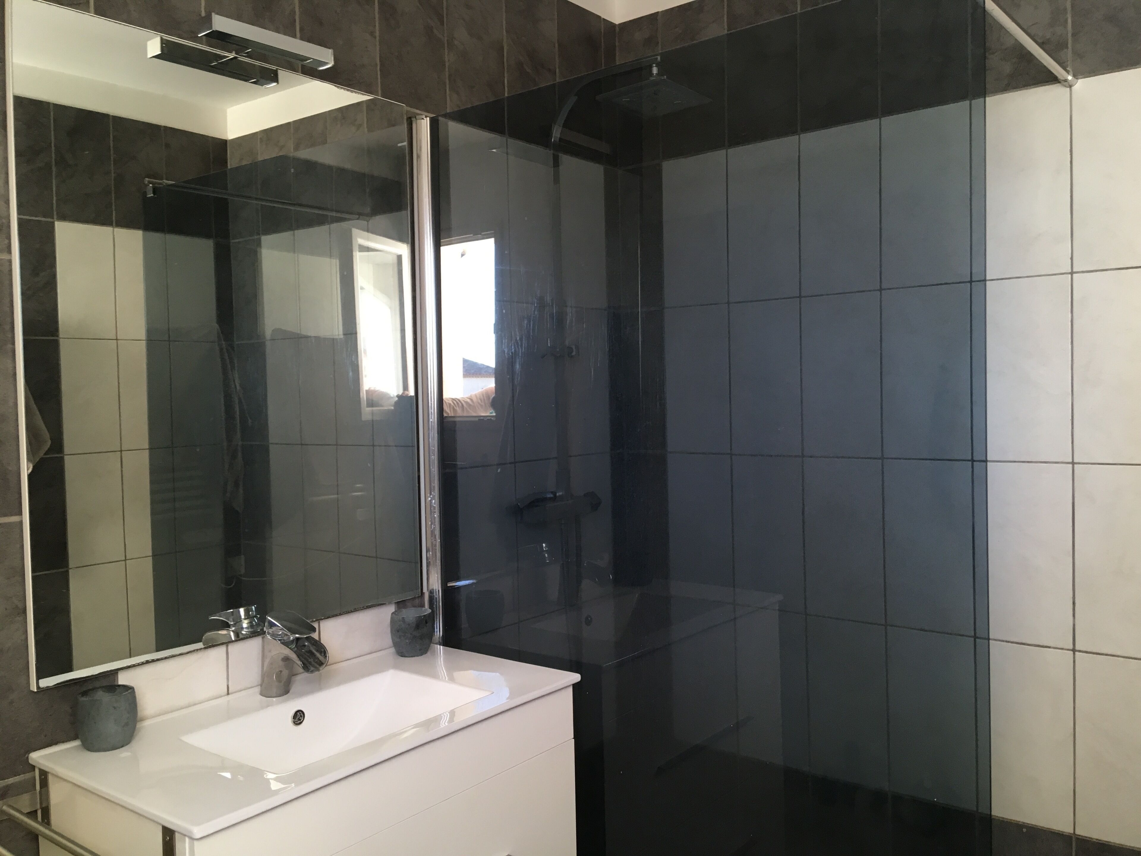 A modern bathroom with a white sink, a large mirror, and a glass shower enclosure.