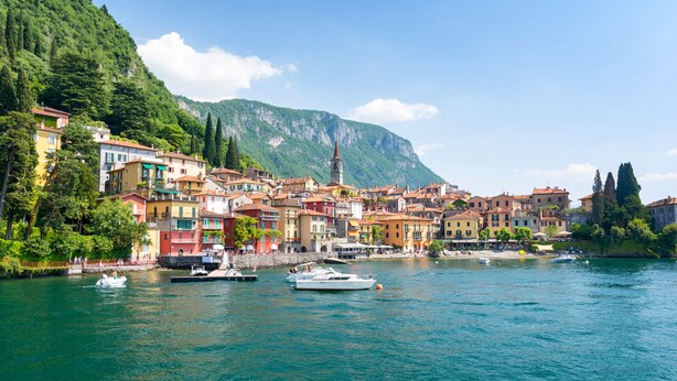 Une ville pittoresque située au bord de l’eau, avec des bâtiments aux couleurs vives, un clocher d’église et des bateaux sur l’eau.