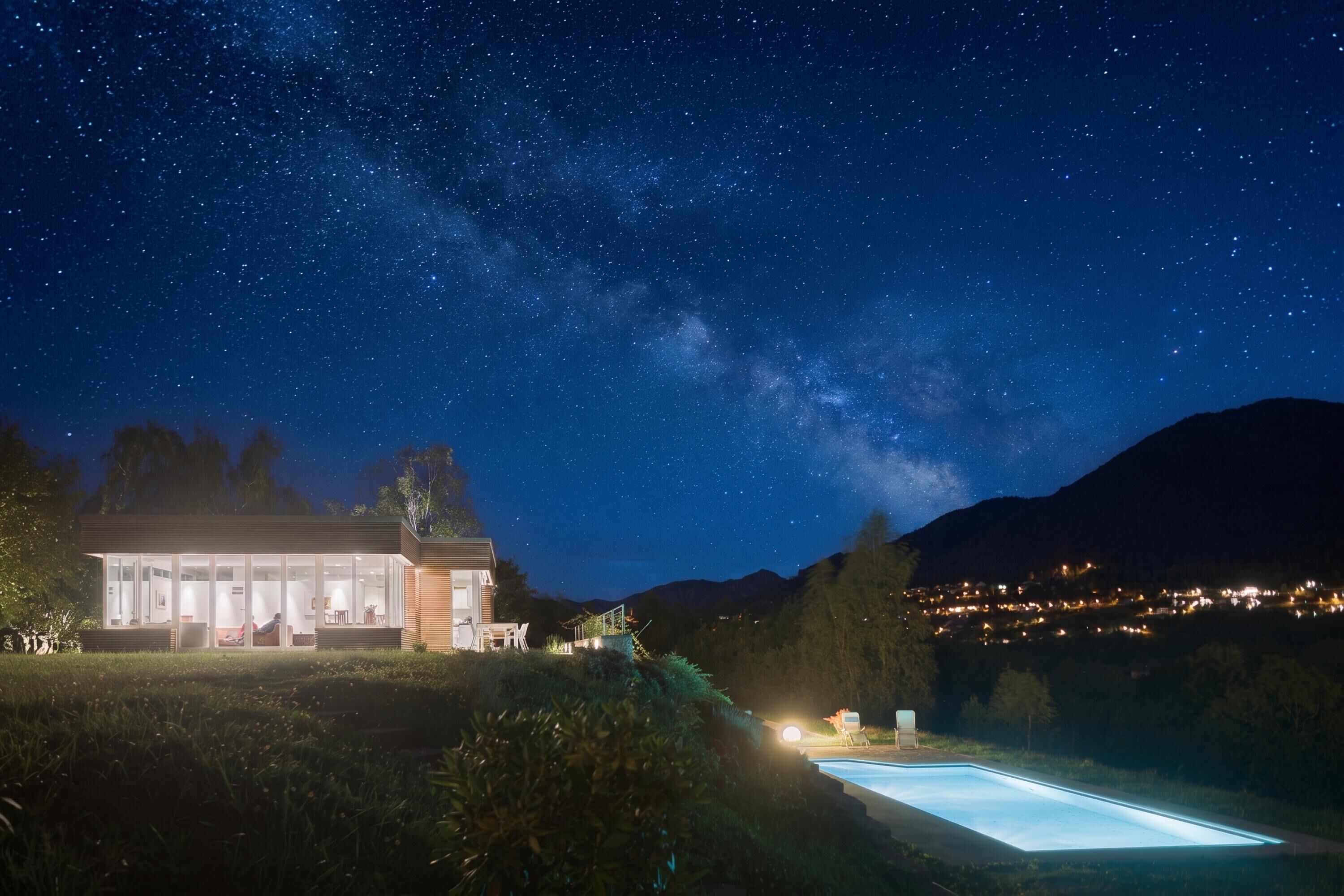 Uma casa moderna com piscina, sob um céu estrelado.