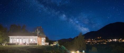 Uma casa moderna com piscina, sob um céu estrelado.