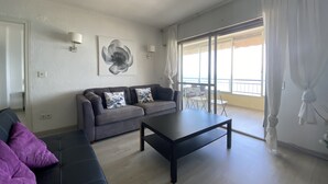 A modern living room with a grey sofa, a black coffee table, and a large window with curtains. - Beautiful Seafront 3Bed, 2Bath, wifi, first line in Altea (Altea)