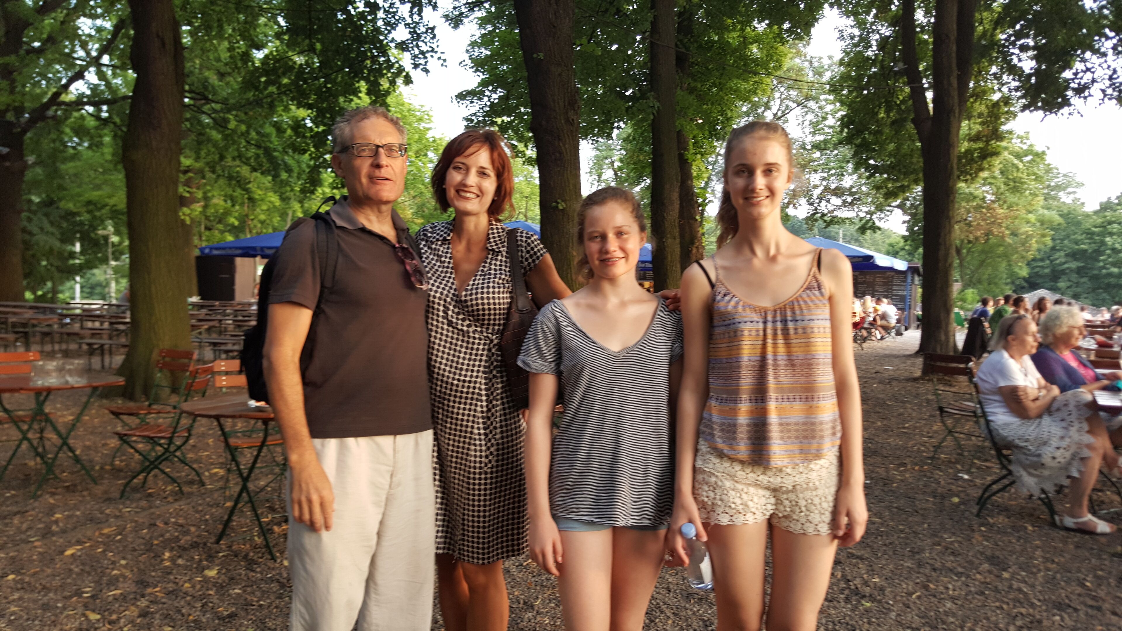 A group of people standing in a park with picnic tables and benches.