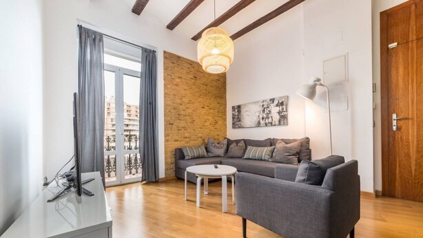 Un salon moderne avec un canapé gris, une table basse ronde et un luminaire suspendu.