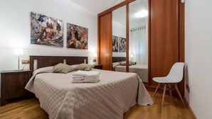 Une chambre à coucher avec un lit, des tables de chevet, une chaise et des œuvres d’art accrochées au mur.