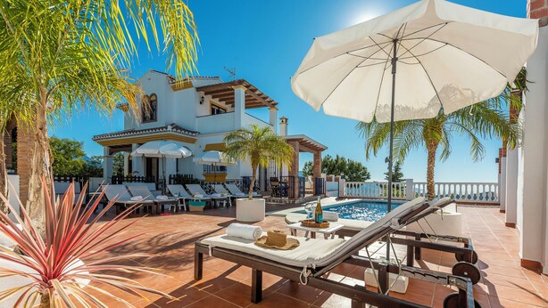 Un espace aménagé au bord de la piscine, avec des chaises longues, une piscine et un grand parasol.