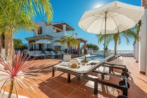 A poolside area with lounge chairs, a pool, and a large umbrella. - Breathtaking views, big swimming pool, Balinese bed, Jacuzzi, Gym ... a dream. (Torrox)