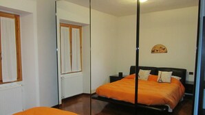 Un dormitorio con cama, mesita de noche, espejo y radiador.