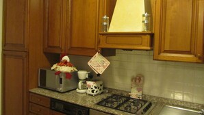 Una cocina con armarios de madera, estufa, tostadora, cafetera y una figurita decorativa de un cerdo.