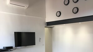 A modern kitchen with a wooden table, black chairs, a flat-screen TV, and four wall clocks. - 2 rooms MASSENA pedestrian zone WIFI - CLIM (Nice)