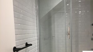A modern bathroom with a glass shower enclosure, white tiled walls, and a black sink. - 2 rooms MASSENA pedestrian zone WIFI - CLIM (Nice)