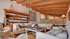 Uma sala de estar aconchegante com uma estante de madeira, uma mesa de centro e um conjunto de sofás.