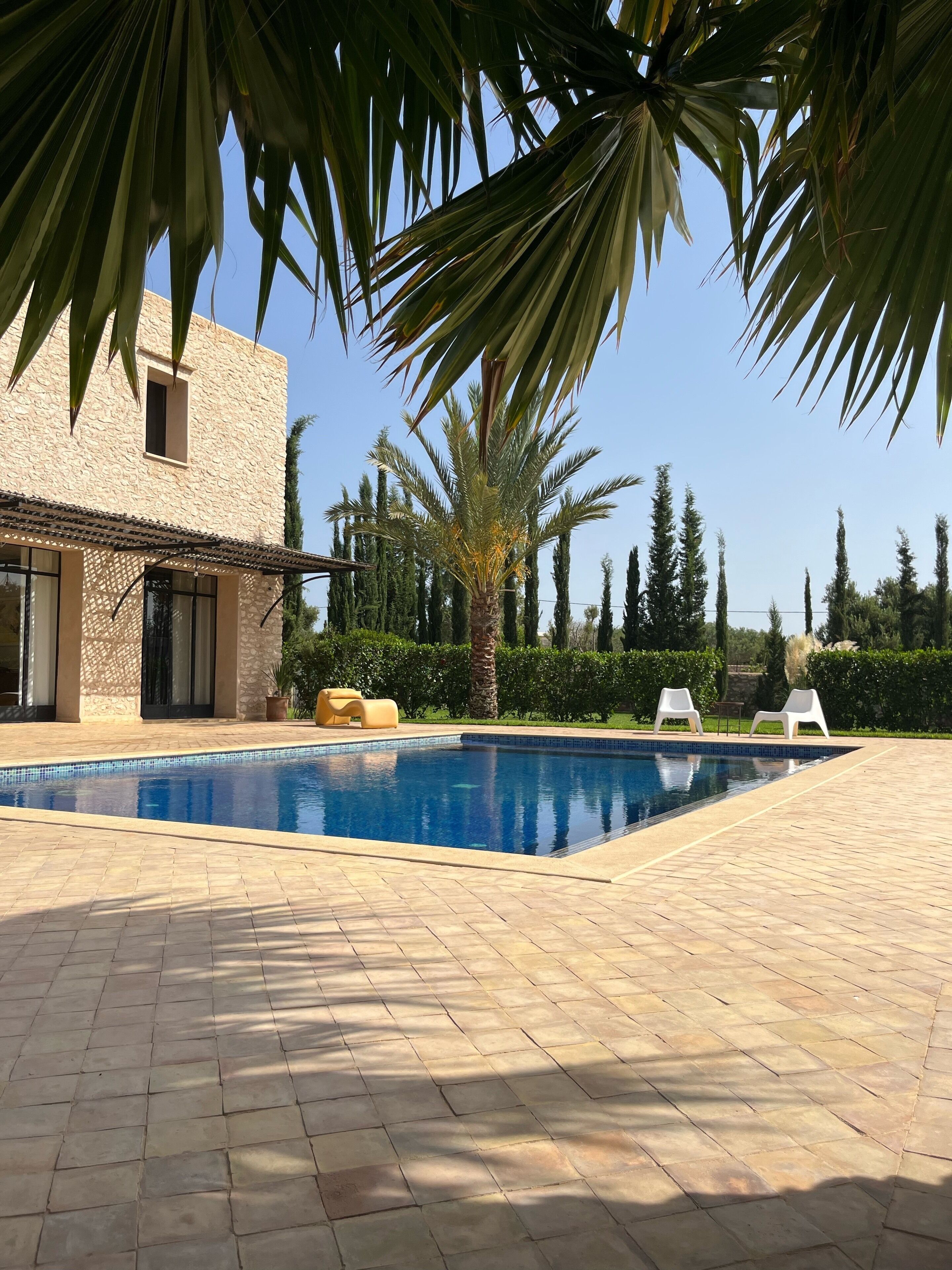 Une piscine dont les bords sont recouverts de carreaux, entourée d’une terrasse dallée.