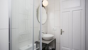 A bathroom with a glass shower enclosure, a white sink, and a mirror. - Singular Stays Parque Central VIII (Valencia)