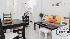 A modern living room with a dining area, featuring a sofa, chairs, a coffee table, and a dining table. - Atocha - 2-Bedroom Apartment in Downtown Madrid (Madrid)
