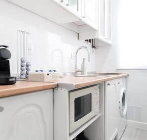 Una cocina compacta con un lavabo, una cafetera y un microondas.