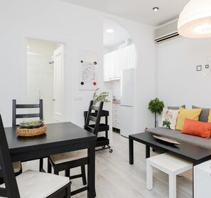 Una sala de estar moderna con comedor, que incluye un sofá, sillas, una mesa de centro y una mesa de comedor.