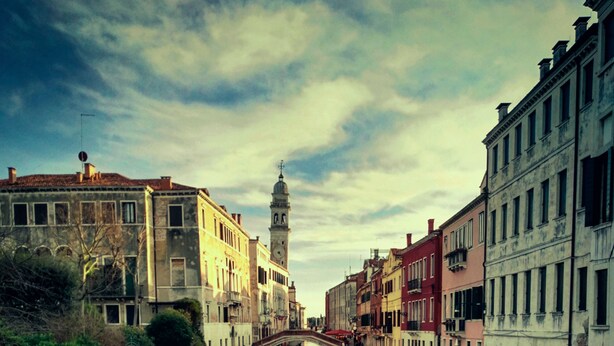 A canal with buildings on either side and a bridge in the middle.