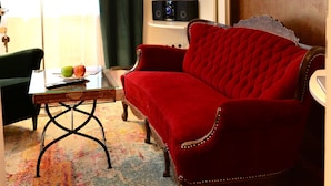 Uma sala de estar com um sofá vermelho, uma mesa de centro de vidro, um abajur e um quadro na parede.