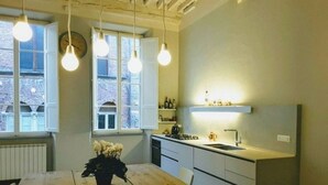 Una cucina compatta con un tavolo di legno, lampadine a sospensione e vista all'esterno attraverso una finestra.