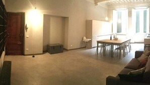 Un'ampia zona giorno con tavolo e sedie da pranzo, un divano e una scala che conduce a un piano superiore.