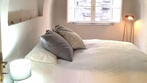 Una camera da letto con un letto, una finestra, una lampada e uno sgabello.
