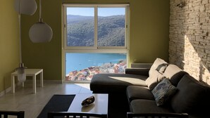 A modern living room with a large window, a stone wall, and a sofa with cushions. - New apartment (128m2), terrace, sea view, A / C, Free Wifi & parking  (Rabac)