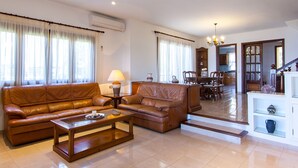 A spacious living room with leather sofas, a coffee table, and a dining area with chairs and a table. - Can Soler - Beautiful chalet with private pool in Alcanada (Alcúdia (Alcanada))