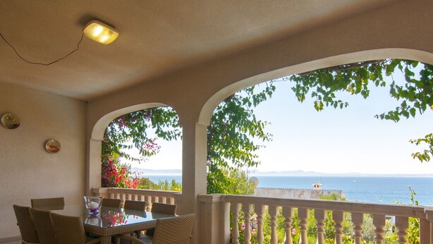 A balcony with a table and chairs, overlooking a scenic view of the sea and greenery. - Can Soler - Beautiful chalet with private pool in Alcanada (Alcúdia (Alcanada))