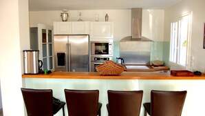 A modern kitchen with stainless steel appliances, a wooden countertop, and four brown chairs. - House / Villa - Saint Chels (Saint-Chels)