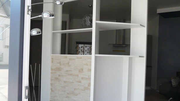 A modern interior with a white built-in closet, a stone backsplash, and a tiled floor.