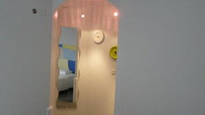 A bedroom with a bed, a door leading to another room, and a ceiling with a unique design.