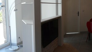 A modern living room with a fireplace, a TV mounted on a white wall, and a red chair.