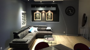 A modern living room with a sectional sofa, a glass coffee table, and artwork on the walls.