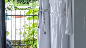 Habitación con vista a una piscina, una bañera blanca y un perchero con toallas blancas.