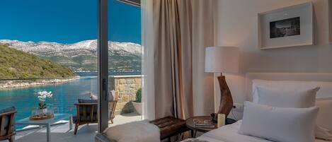 A hotel room with a large window offering a view of a coastal landscape.