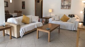 Una sala de estar con dos sofás, una mesa de centro, una lámpara y un cuadro en la pared.
