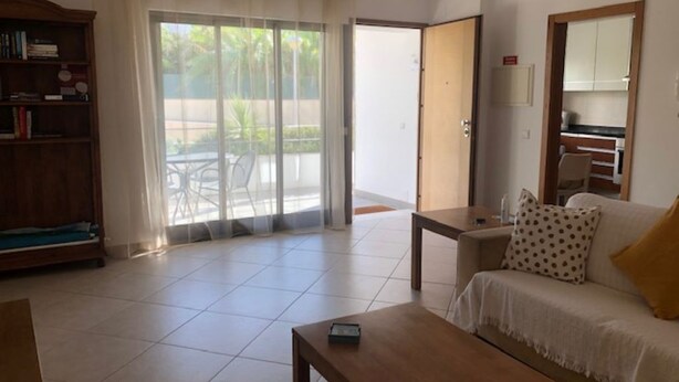 Una sala de estar con un sofá, una mesa de centro, una estantería y un ventanal corredizo que da a un espacio exterior.