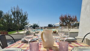 A table set for dining with a view of a swimming pool and trees. - "House Sbrizza" in the countryside 15 minutes from the sea (Rosolini)