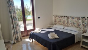A bedroom with a bed, a nightstand, a window with curtains, and a view of the outside. - "House Sbrizza" in the countryside 15 minutes from the sea (Rosolini)