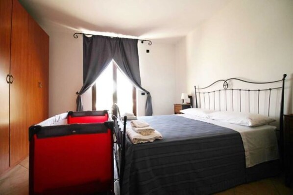 A bedroom with a bed, a nightstand, a wardrobe, and a red suitcase.