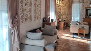 A cozy living room with a sofa set, a stone wall, and a wooden ceiling.
