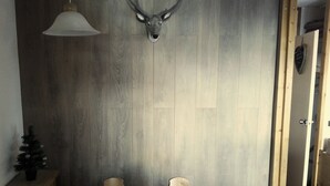 A room with a wooden wall, a deer head mounted above a table with a grid pattern, and a small Christmas tree on a cabinet. - Nice renovated apartment ** Terrace, skiing, parking, shops at 30m (La Plagne Tarentaise)