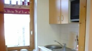 A small kitchen with wooden cabinets, a white sink, and a dishwasher. - Nice renovated apartment ** Terrace, skiing, parking, shops at 30m (La Plagne Tarentaise)