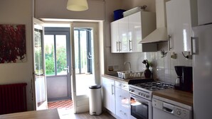 Una cocina con armarios blancos, estufa, fregadero y cubo de basura.
